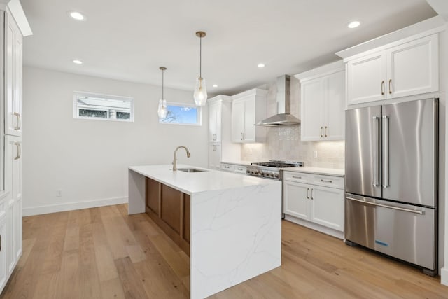 kitchen featuring white cabinetry, light stone countertops, high quality fridge, and wall chimney range hood