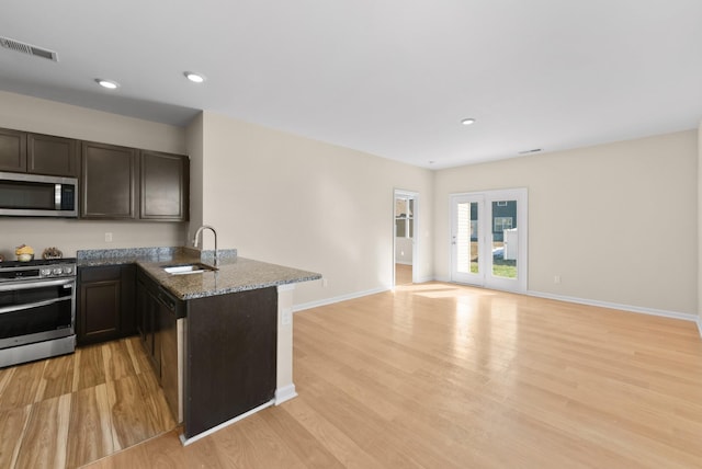 kitchen with stainless steel appliances, sink, stone countertops, kitchen peninsula, and light hardwood / wood-style flooring