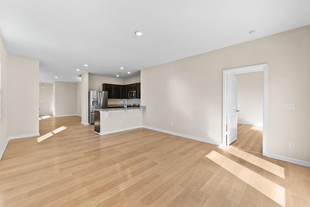 unfurnished living room with sink and light hardwood / wood-style floors