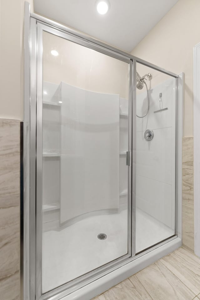 bathroom featuring a shower with shower door and tile walls