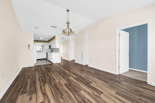 unfurnished living room featuring dark hardwood / wood-style flooring, a chandelier, and vaulted ceiling