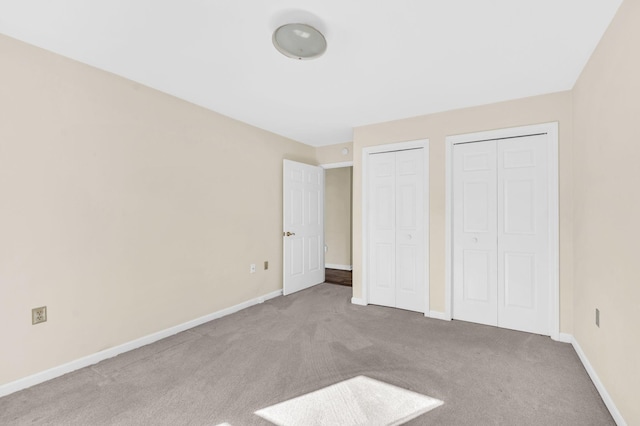 unfurnished bedroom featuring multiple closets and carpet