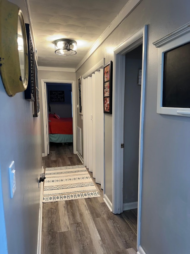 hall with crown molding, baseboards, and dark wood-style flooring