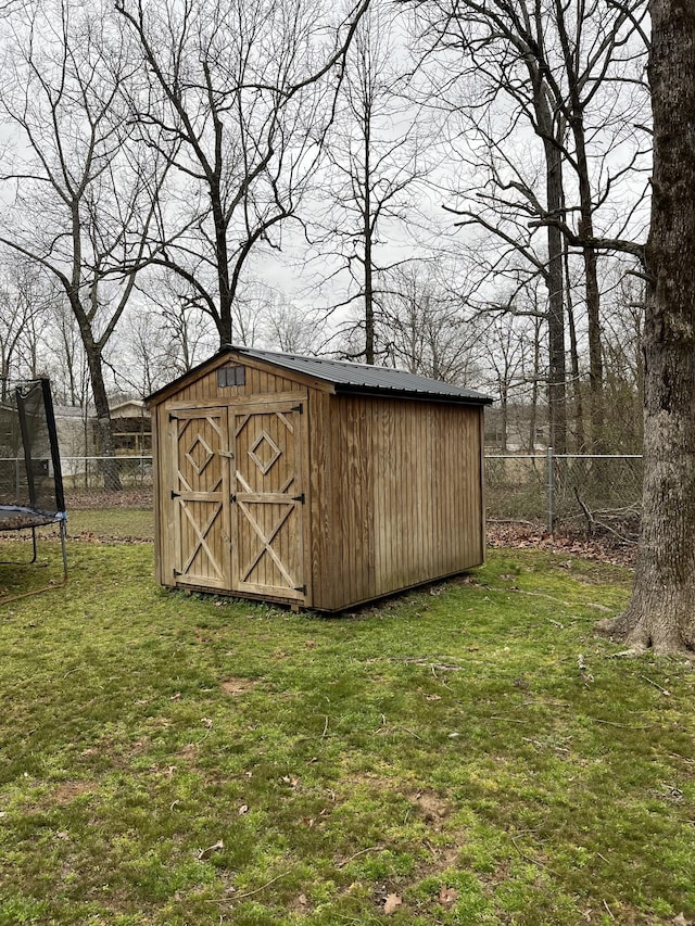 view of shed with a trampoline and fence