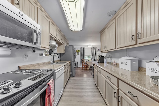 kitchen with appliances with stainless steel finishes, light hardwood / wood-style floors, and sink