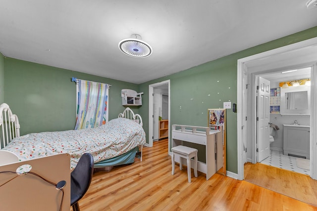 bedroom with radiator, light hardwood / wood-style floors, connected bathroom, and sink