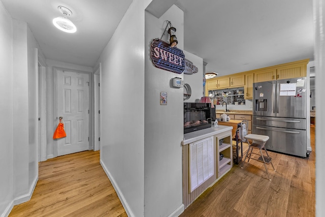 kitchen featuring stainless steel fridge with ice dispenser, light brown cabinetry, light hardwood / wood-style flooring, and sink