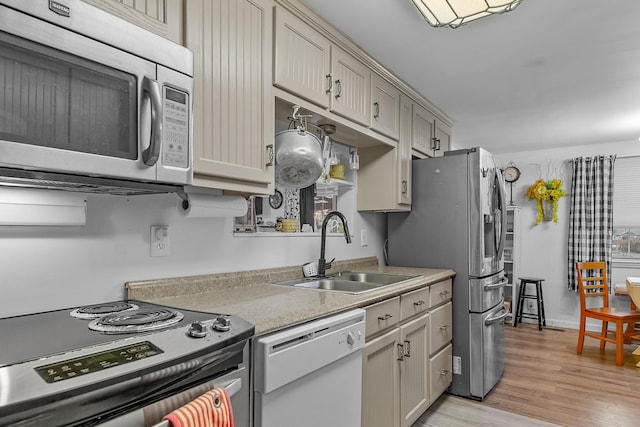 kitchen with sink, appliances with stainless steel finishes, and light hardwood / wood-style flooring