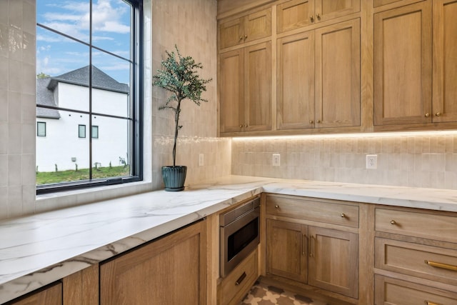 kitchen with light stone counters, backsplash, and stainless steel microwave