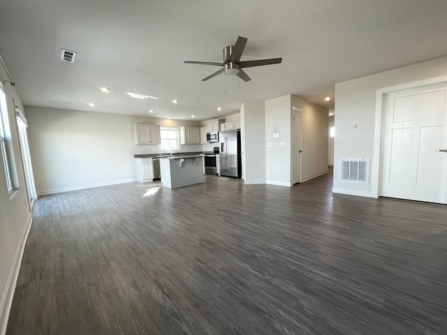 unfurnished living room with dark wood-type flooring, sink, and ceiling fan