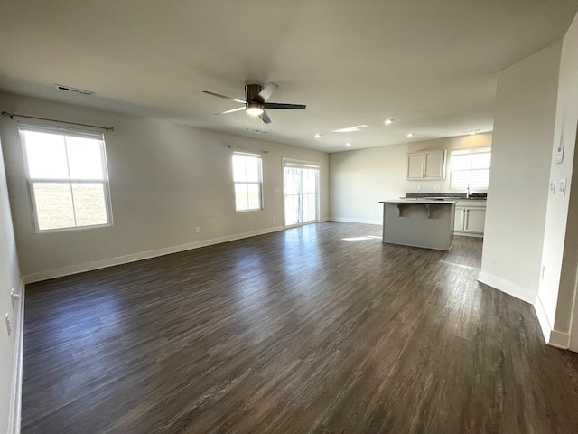 unfurnished living room featuring ceiling fan, sink, and dark hardwood / wood-style flooring