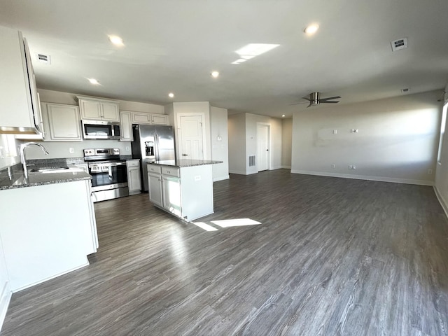 kitchen with ceiling fan, appliances with stainless steel finishes, a kitchen island, white cabinets, and sink