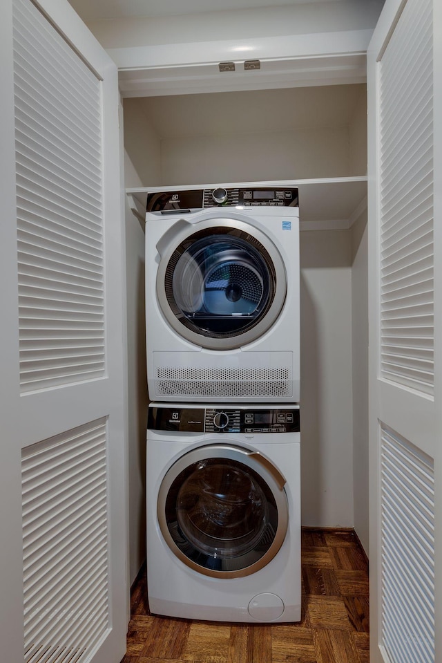 laundry room with dark parquet floors and stacked washer and clothes dryer