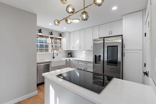 kitchen featuring light hardwood / wood-style floors, appliances with stainless steel finishes, pendant lighting, white cabinets, and sink