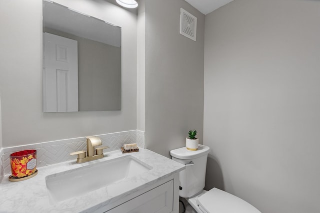 bathroom featuring backsplash, toilet, and vanity