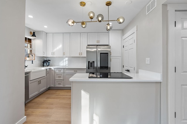 kitchen with white cabinets, appliances with stainless steel finishes, kitchen peninsula, and tasteful backsplash