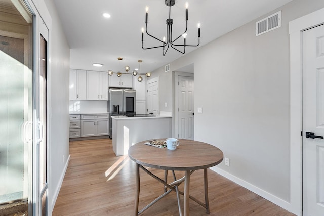 dining room featuring light wood-type flooring and an inviting chandelier