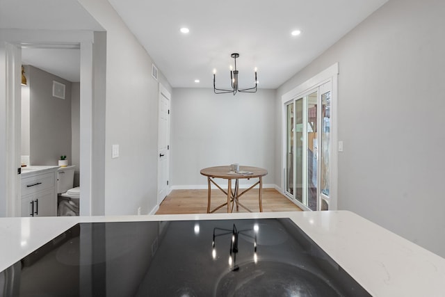 kitchen with light hardwood / wood-style floors, pendant lighting, white cabinets, and a chandelier