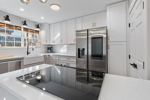 kitchen with decorative backsplash, white cabinets, appliances with stainless steel finishes, and sink