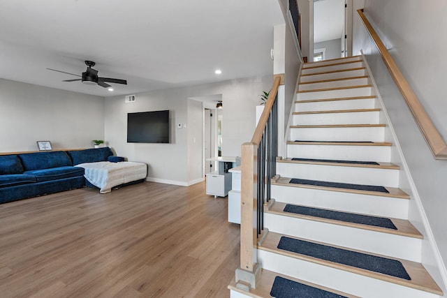 staircase with ceiling fan and wood-type flooring