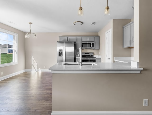 kitchen featuring pendant lighting, appliances with stainless steel finishes, an inviting chandelier, sink, and gray cabinets