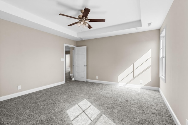 carpeted empty room with ceiling fan and a tray ceiling