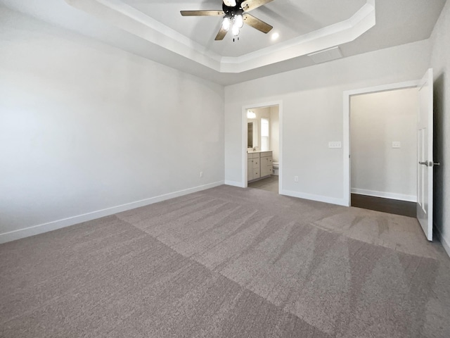 unfurnished bedroom with ceiling fan, connected bathroom, a tray ceiling, and carpet floors