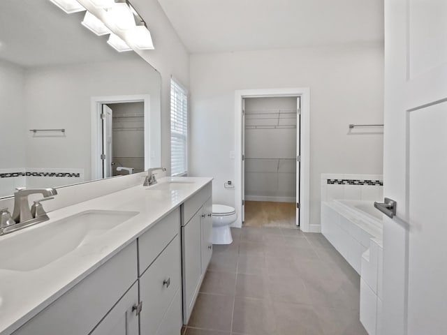 bathroom featuring toilet, vanity, tile patterned flooring, and tiled tub