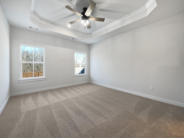 carpeted spare room featuring ceiling fan and a tray ceiling