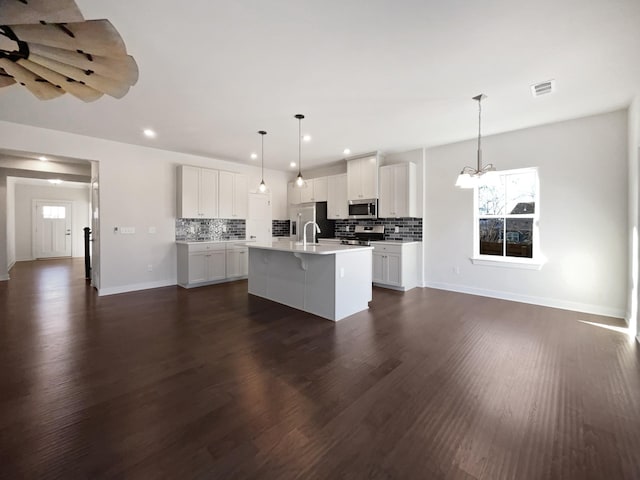 kitchen featuring pendant lighting, a center island with sink, sink, appliances with stainless steel finishes, and white cabinets