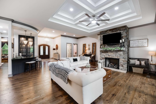 living room featuring dark wood-type flooring, crown molding, a stone fireplace, and coffered ceiling