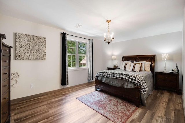 bedroom with hardwood / wood-style flooring and a notable chandelier