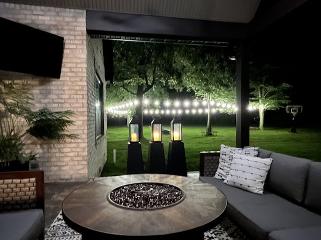 patio at night featuring a lawn and an outdoor fire pit