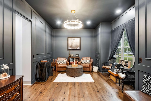 living area featuring ornamental molding, a chandelier, and light hardwood / wood-style flooring