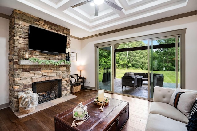 living room featuring wood-type flooring, a stone fireplace, ceiling fan, crown molding, and coffered ceiling