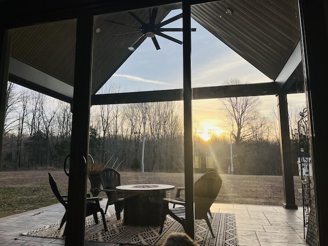 patio terrace at dusk featuring ceiling fan and a fire pit