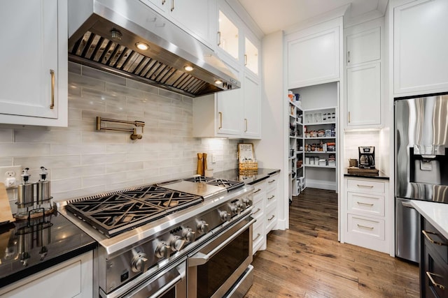 kitchen featuring range hood, appliances with stainless steel finishes, decorative backsplash, and white cabinets