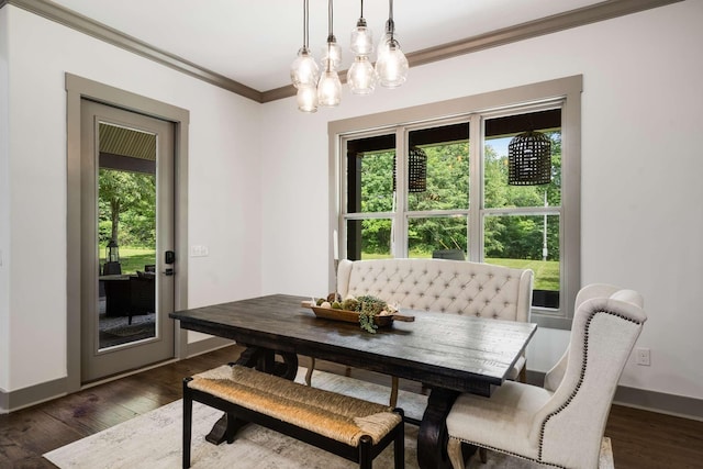 dining space featuring dark wood-type flooring, crown molding, and an inviting chandelier