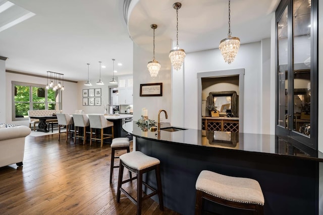 bar with dark wood-type flooring, sink, pendant lighting, and ornamental molding