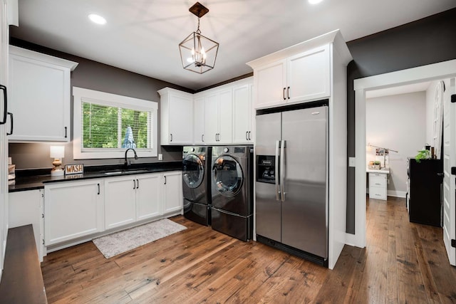 laundry room featuring cabinets, dark wood-type flooring, sink, a chandelier, and independent washer and dryer