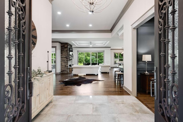 entrance foyer featuring a raised ceiling, a notable chandelier, and ornamental molding