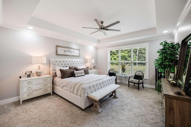 carpeted bedroom with ceiling fan and a raised ceiling