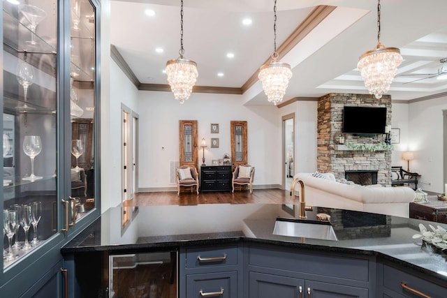 bar featuring a stone fireplace, dark hardwood / wood-style floors, decorative light fixtures, wine cooler, and sink