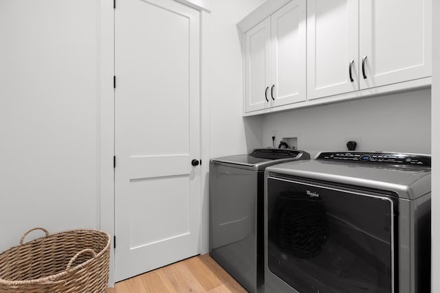 clothes washing area featuring washer and dryer, cabinets, and light wood-type flooring