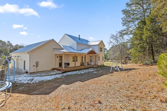 rear view of property featuring a trampoline, a wooden deck, and a garage