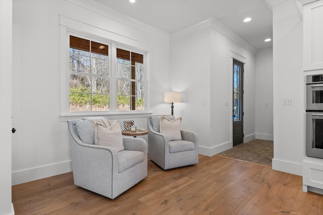 sitting room with light hardwood / wood-style flooring and ornamental molding