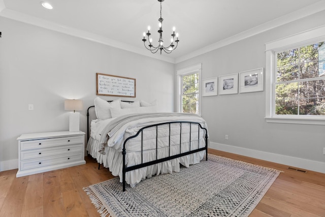 bedroom with multiple windows, ornamental molding, an inviting chandelier, and light wood-type flooring