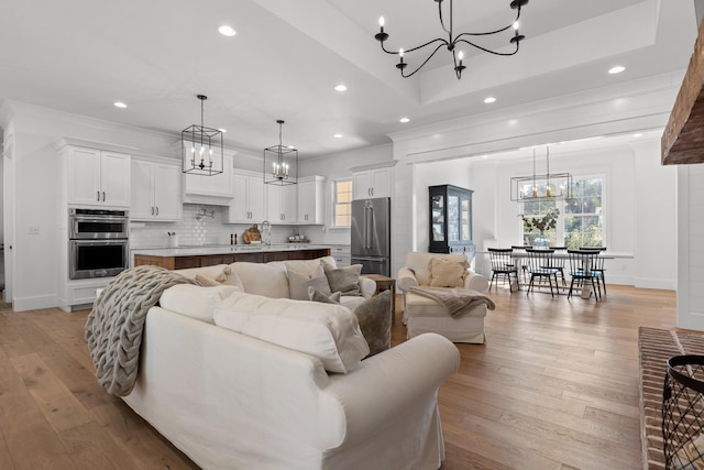 living room with sink, ornamental molding, and light hardwood / wood-style floors