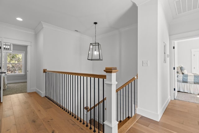 corridor with light wood-type flooring and crown molding