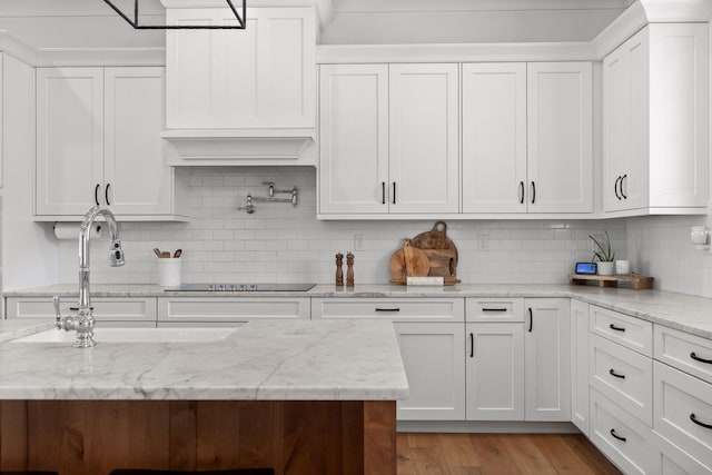 kitchen with white cabinetry, black electric stovetop, and tasteful backsplash